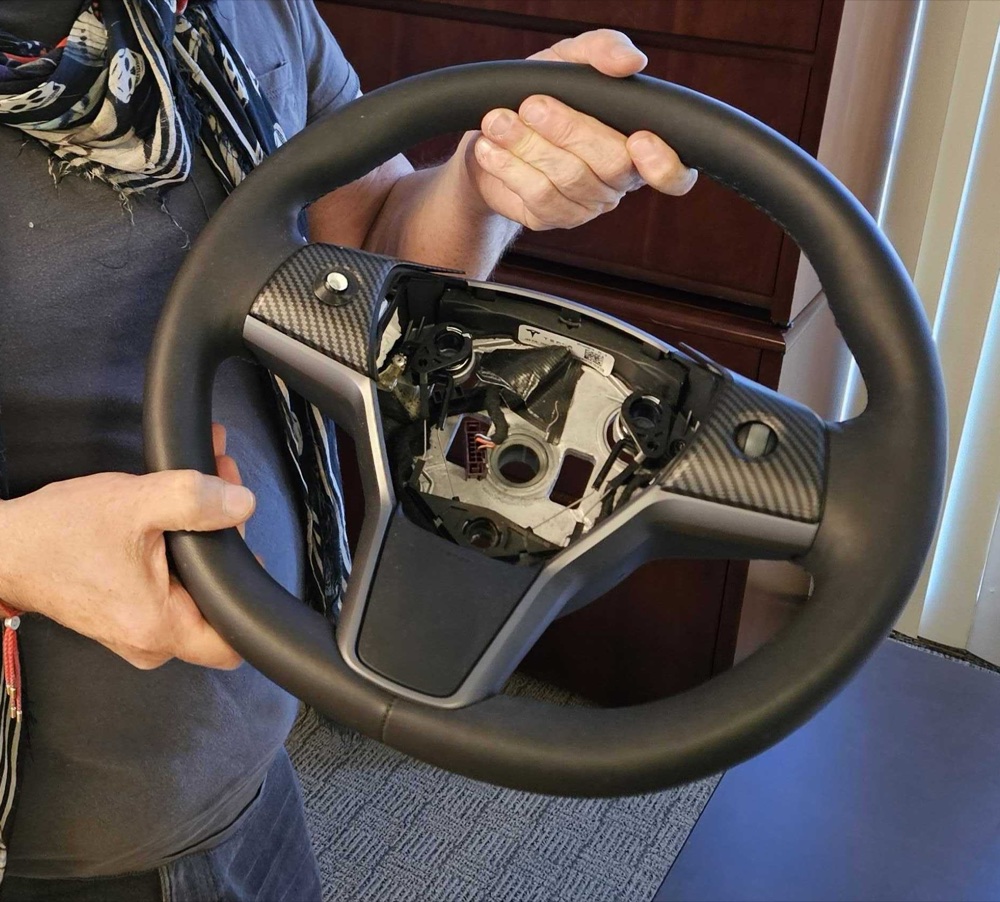 Hands holding a Tesla steering wheel, opened up and fitted with Aerendir® grip sensors.